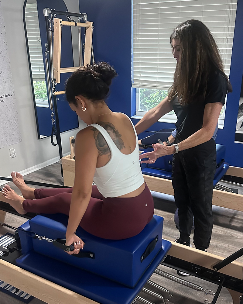 A Teacher giving hands-on corrections during a Pilates session at Lucie Lemon Pilates in Port St. Lucie